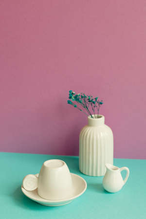 White coffee cup and vase of dry flower on mint green table. pink wall backgroundの写真素材