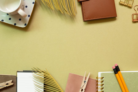 Notebook, clip, cup, pencil, plant on khaki green background. workspace. flat lay, top view, copy...