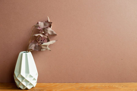 Vase of dry flowers on wooden table. brown wall background. home interior