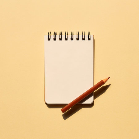Blank notebook and colored pencil on beige background. top view, copy space