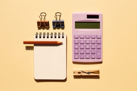 Notepad, colored pencil, calculator on beige background. top view, copy space
