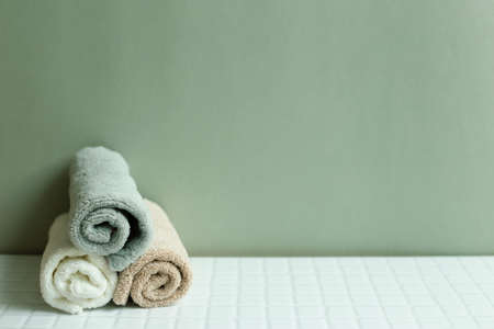 Bathroom towel on white table. khaki green wall background. skin care and spa conceptの写真素材