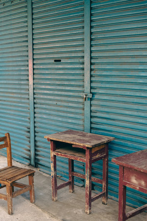 Abandoned wooden desk and chair in front of blue shutter door in Taiwanの写真素材