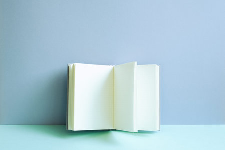 Open notebook on blue desk. blue wall background