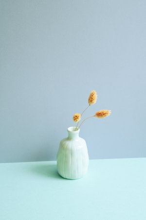 Vase of pink dry flower on blue table. blue wall background. minimalism home decorの写真素材