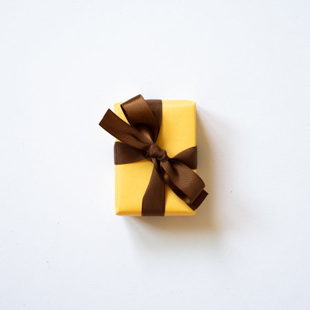Yellow gift box and brown ribbon isolated on white background. top view, copy spaceの写真素材