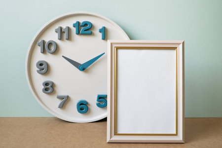 Blank picture frame with clock on brown shelf. mint wall background. copy spaceの写真素材