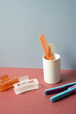 Hair dresser tool. Hairbrush and hairpin, hair straightener iron on red table. gray wall backgroundの写真素材