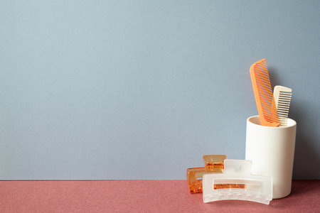 Hair dresser tool. Hairbrush and hairpin on red table. gray wall backgroundの写真素材