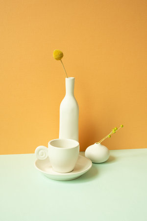 Minimal white ceramic coffee cup and vase of flower on mint green table. orange wall backgroundの写真素材