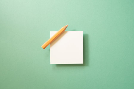 White memo paper, sticky note pad with colored pencil on green background. top view, copy spaceの写真素材