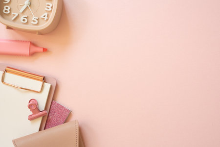 Pink notebook, clipboard, clip, pouch, highlighter, clock on pink desk background. flat lay, top view, copy space. workspaceの写真素材