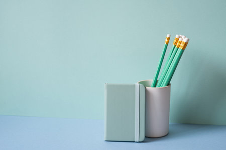 Pencil holder and diary notebook on blue desk. mint green backgroundの写真素材