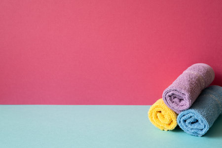 Stack of bathroom shower towels on skyblue shelf. pink wall backgroundの写真素材