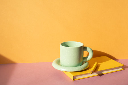 Notebook and colored pencil, coffee cup on pink desk. orange wall background. workspaceの写真素材
