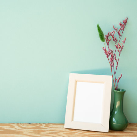 Wooden photo frame and vase of dry flower on wooden shelf. mint wall backgroundの写真素材
