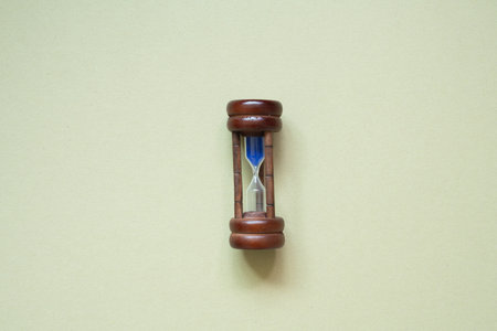 Wooden hourglass sandglass isolated on khaki background. top view