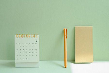 Calendar and notepad, pen for schedule, business, vacation plan on mint green desk backgroundの写真素材