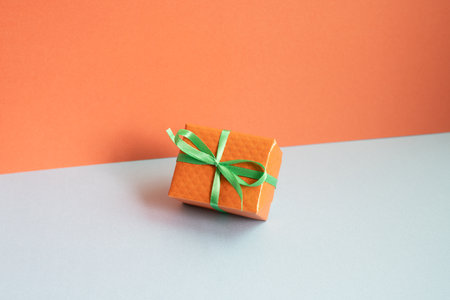 Orange gift box on gray desk. red wall backgroundの写真素材