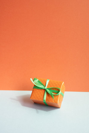 Orange gift box on gray desk. red wall backgroundの写真素材