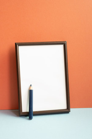 Empty photo frame with colored pencil on gray shelf. red wall backgroundの写真素材