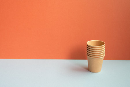 Disposable kraft paper cups on gray table. red wall backgroundの写真素材