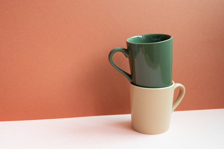 Khaki and beige mug cups on pink table. red backgroundの写真素材