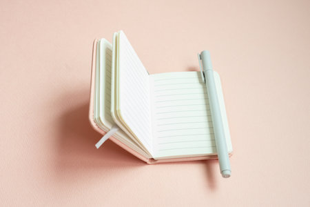 Open lined notebook and pen on pink desk backgroundの写真素材