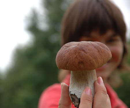 Girl holding Boletus mushroom in hand in front of herの写真素材