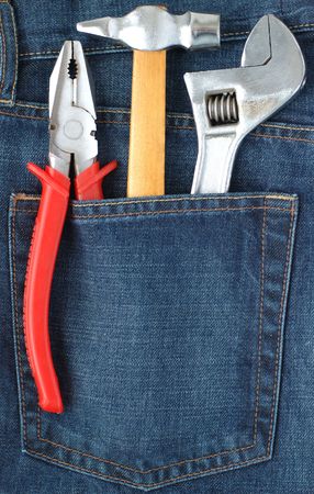 Toolkit of hammer, adjustable spanner and combination pliers in a blue jeans pocketの写真素材