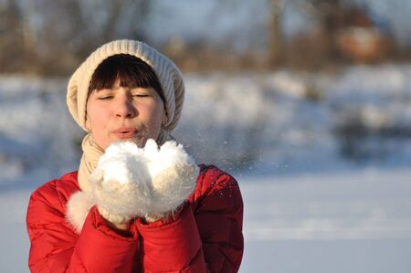 Photo of young woman blowing snow from her handsの写真素材