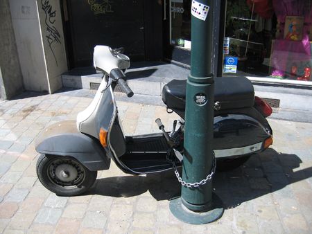 Scooter chained to post on streetの写真素材