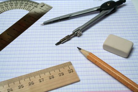 Compasses, pencil, eraser and rulers on squared paperの写真素材
