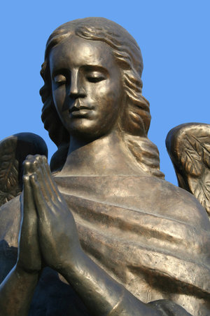 Fragment of a bronze sculpture of a praying angel on a background of the sky the front view in details, Isolated (look similar images in my portfolio)の写真素材