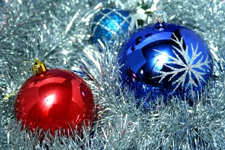 Two New Year's glass spheres of dark blue and red color with a pattern on a background of a christmas tinselの写真素材
