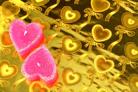 Two candles in the form of hearts on a golden background の写真素材