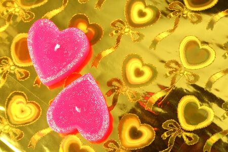 Two candles in the form of hearts on a celebratory background の写真素材
