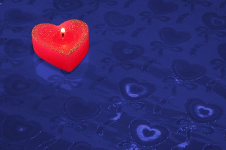 Red candle in the form of heart on a dark blue background の写真素材