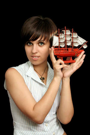 The nice girl with the toy ship in a hand, isolated on black backgroundの写真素材