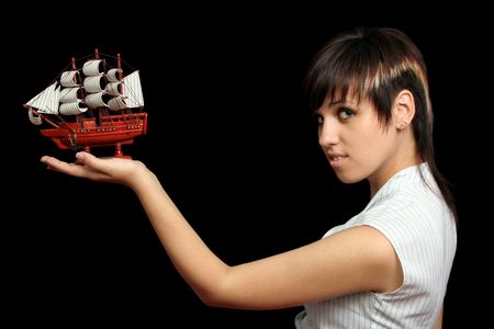 The nice girl with the toy ship in a hand, isolated on black backgroundの写真素材