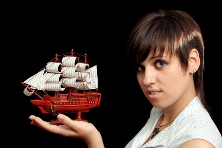 The nice smiling girl with the toy ship in a hand, isolated on black backgroundの写真素材
