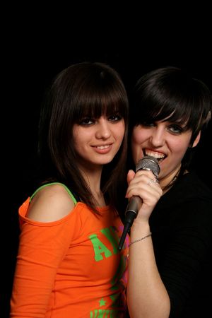 Two girls with a microphone, on black backgroundの写真素材