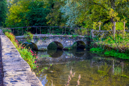A small vintage stone bridge over river Coln that leads to Arlington Row of Bibury village in Cotswold district, Gloucestershire, England, UKの写真素材