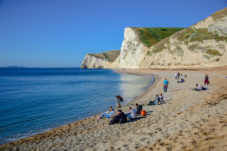 Tourists enjoying their time at a beautiful landscape and seascape view of Durdle Door, a natural limestone arch on the Jurassic Coast near Lulworth in Dorset, England, United Kingdomのeditorial素材