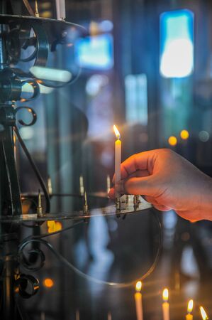 A Buddhist lights and holds a candle to worship and praise the Buddha in a Buddhism templeの写真素材