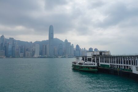 Tsim Sha Tsui Pier at Victoria Harbor with popular Hong Kong island landmark in backgroundのeditorial素材