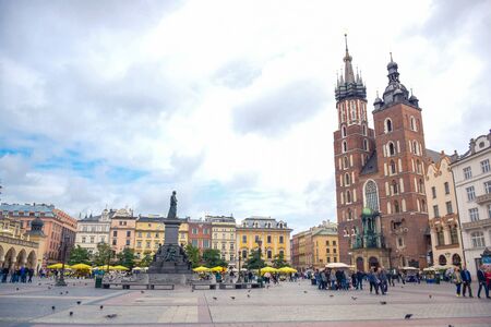 Tourists enjoying their time walking and strolling at Krakow's Main Square with Adam Mickiewicz Monument and St. Mary's Basilica in city of Krakow, Polandのeditorial素材