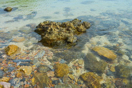 Crystal clear shallow sea water showing rocks underneathの写真素材
