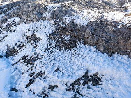 rocky coast in winter with snow and ice, Snow Melting Gradually on The Ground of Mountain Formed A Pattern of Ice Shape In Summer Timeの写真素材