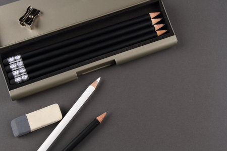 Black and white pencils with eraser on a grey background
